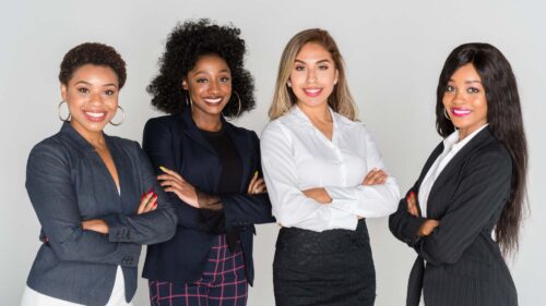 Four women of color standing in suits