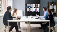 Meeting with employees connecting by video conference and in the office