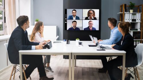 Meeting with employees connecting by video conference and in the office
