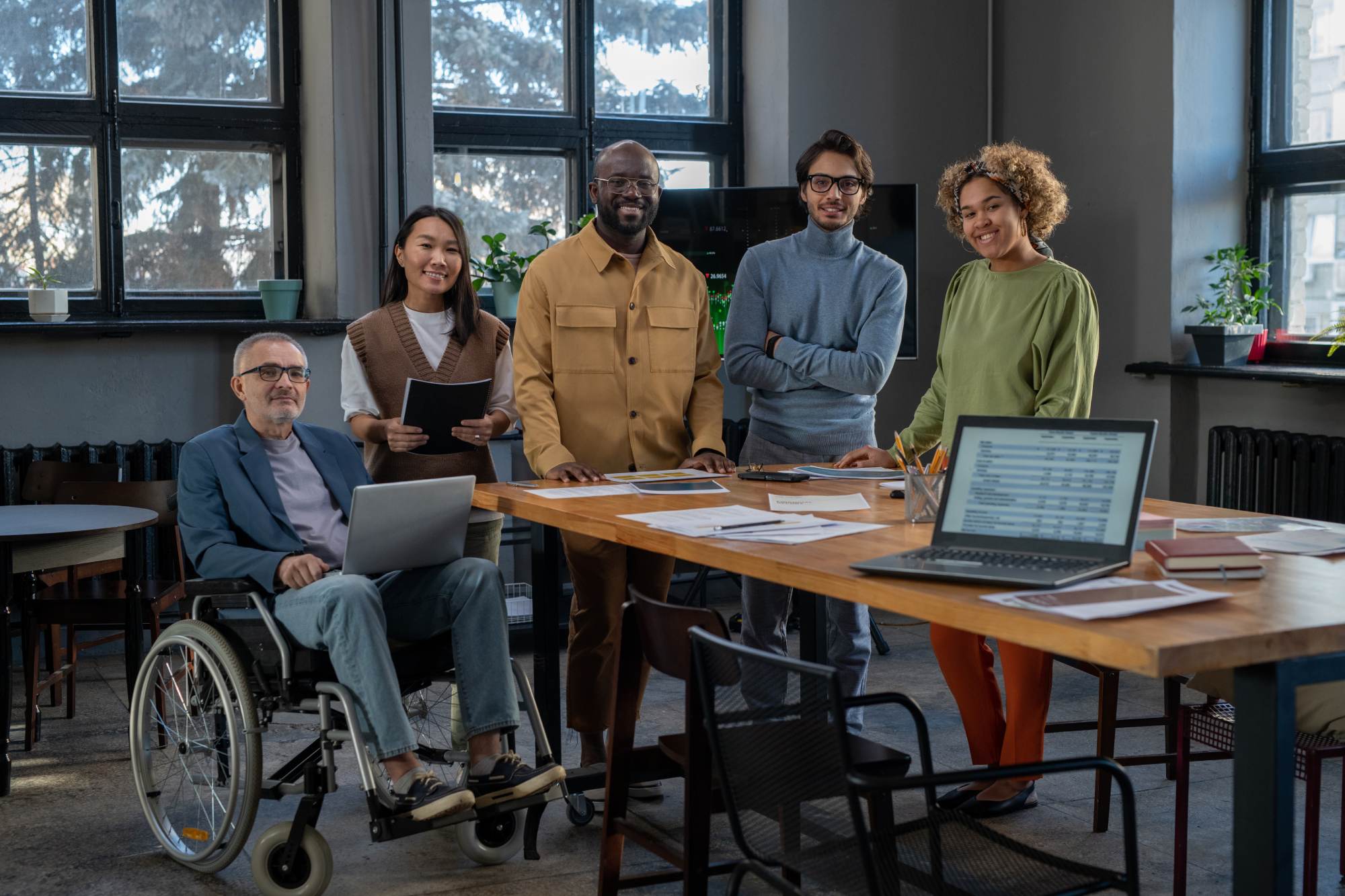 Group of employees in an office including a man in a wheelchair, an Asian women and two Black people